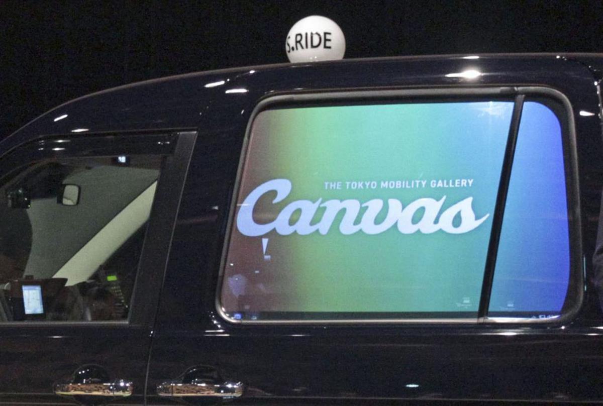 タクシーの左後部座席の窓に投影されたデジタルサイネージ（共同）