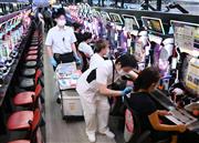 パチンコ店内の遊技機の前でワクチン接種を受ける人々＝１４日午後、大阪市北区（一部画像処理しています、永田直也撮影）