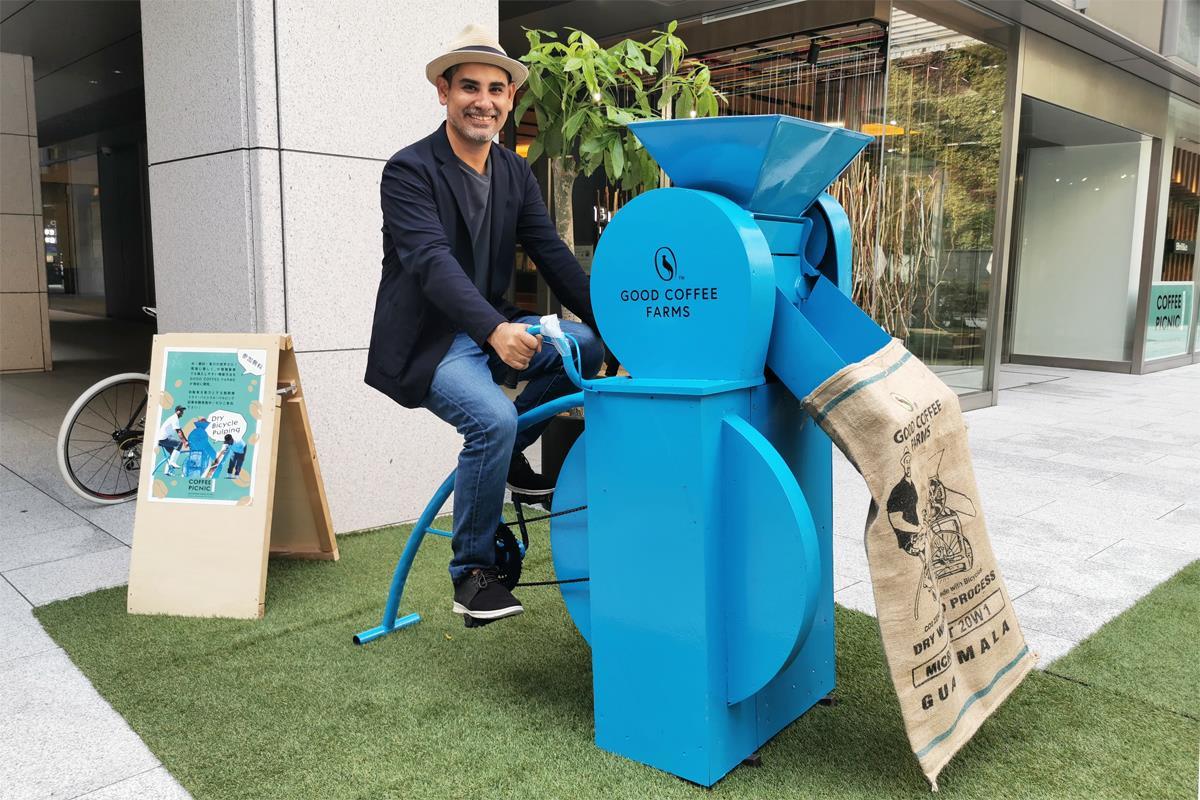 自身が開発した自転車型脱穀機を実演するGOOD COFFEE FARM代表のカルロス・メレンさん。装置上部の開口部から入れたコーヒーチェリーが脱穀され、袋の中に流れ込む仕組み（SankeiBiz編集部）