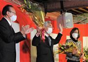 花束を掲げて当選を喜ぶ片岡氏（中央）＝２６日午後９時５５分ごろ、寿都町の後援会事務所（坂本隆浩撮影）